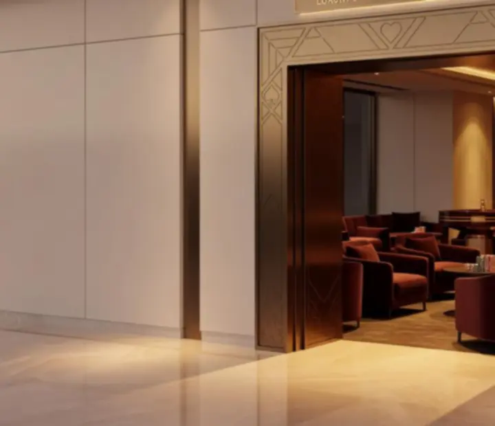 Grand entrance to CEWE Magyarország Korlátolt Felelősségű Társaság with warm ivory walls, brushed bronze finishes and a glimpse of a casino lounge with burgundy seating and a roulette-inspired detail.