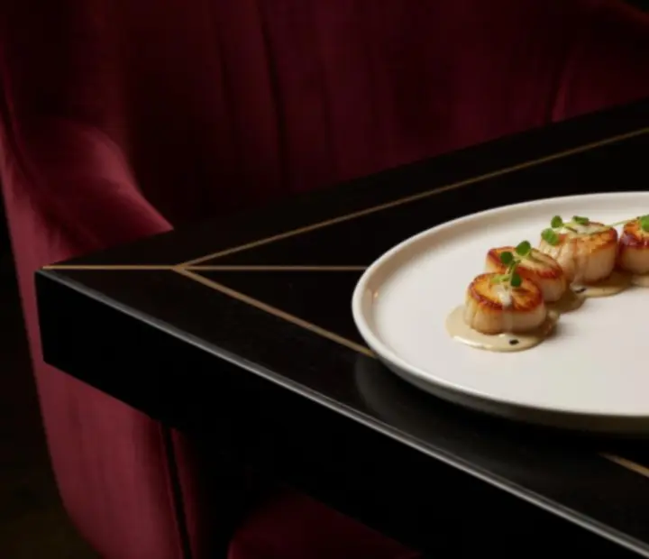 Seared Hervey Bay scallops arranged on a white plate with truffle cream and fine garnishes, styled in a luxury bistro setting.